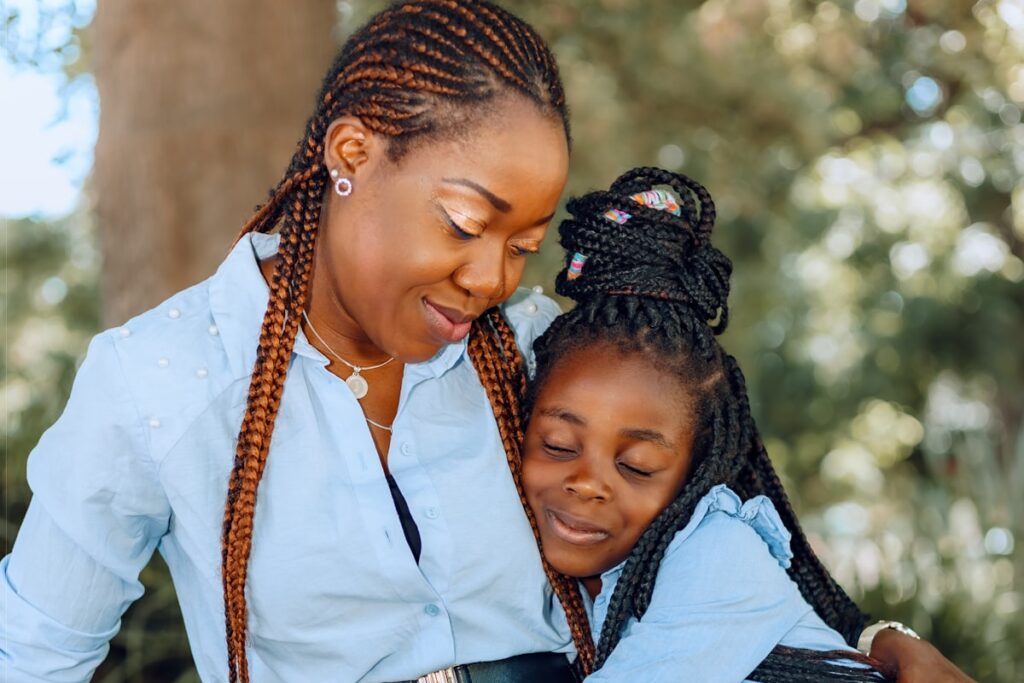 A mother hugging her smiling daughter outdoors