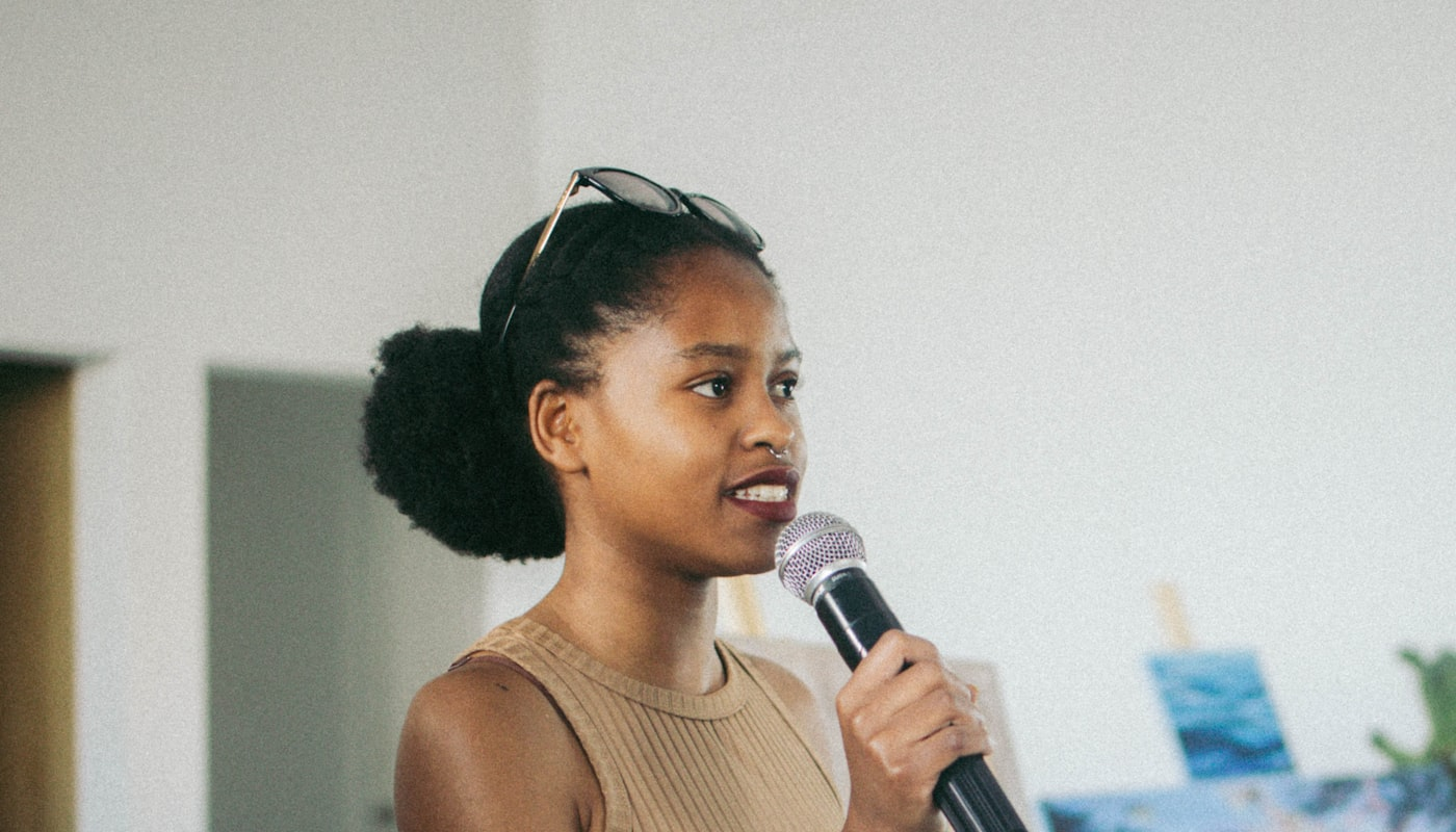 A woman speaking into a microphone to an audience