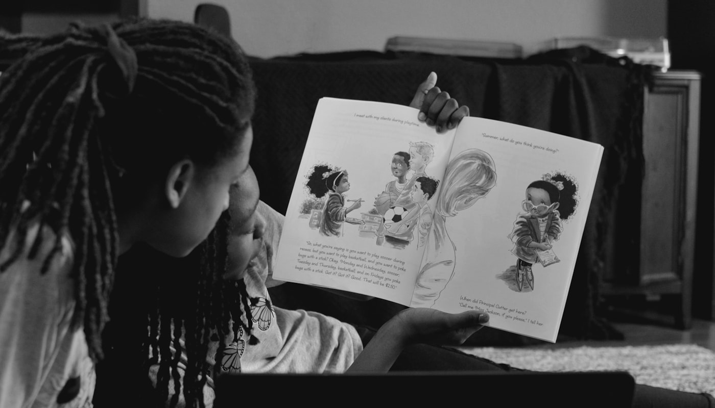 A parent reading a picture book with a young child outdoors