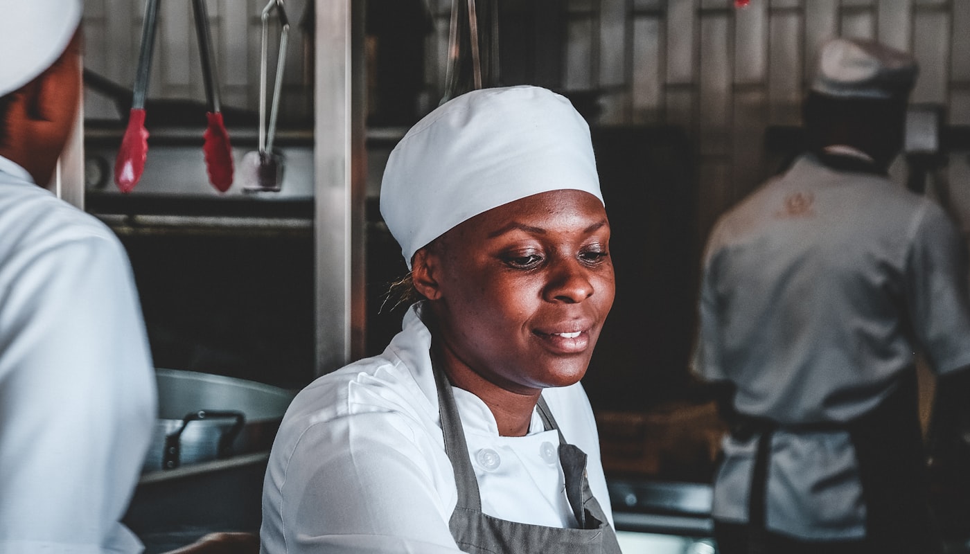 A hospitality trainee in chef whites working in a kitchen